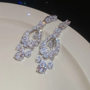 Macro shot of silver drop earrings with sparkling zircons on a ceramic plate