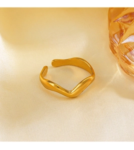 Macro shot of wavy irregular gold plated open ring on champagne silk fabric background