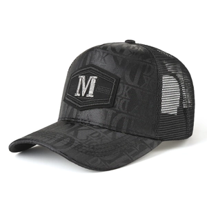 Detail of black mesh trucker hat featuring silver metal M logo and dark DK pattern