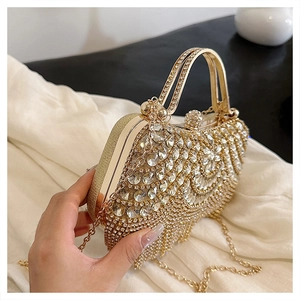 Close-up of golden rhinestone evening clutch bag with metal handle and chain strap