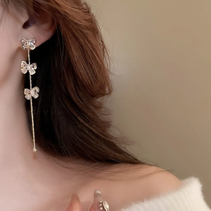 Gros plan de boucles d'oreilles nœud dorées avec de longs glands portées par un mannequin