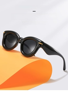 Detail of black thick frame sunglasses with gold metal hinges and UV protection lenses