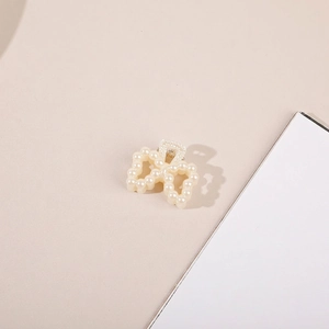 Macro shot of an elegant pearl bow hair claw clip with golden alloy structure