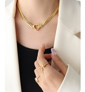 Gros plan d'un collier cœur gourmette doré et bagues assorties sur mannequin en blanc
