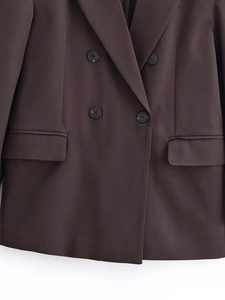 Detailed view of dark brown double-breasted blazer with flap pockets and classic lapel