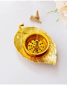 Golden leaf-shaped incense burner detail with cone holder and floral accents