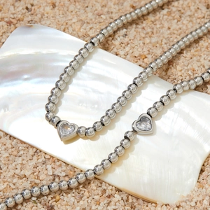 Colliers à billes en acier inoxydable avec pendentifs cœur sur un coquillage de plage