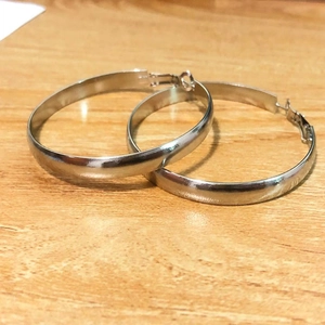 Gros plan de boucles d'oreilles créoles argentées avec fermoir sur une table en bois