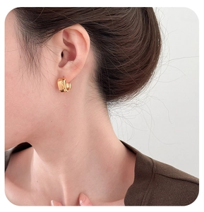 Close-up of a model wearing square polished gold geometric C-shaped earrings