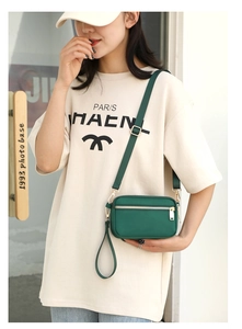 Green nylon crossbody bag with adjustable strap and multiple zipper pockets shown on model