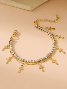 Detail of gold double-layer bracelet with tennis chain crystals and cross pendants