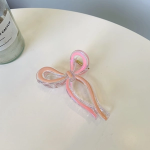 Detail of pink bow hair claw clip with pearlescent finish and gold metal spring