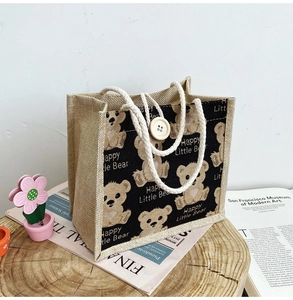 Close-up of durable jute tote bag with cute bear print on a rustic wooden tray