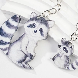 Detail of creative raccoon couple keychains featuring realistic wood-like finish on white stand