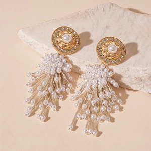 Gros plan de boucles d'oreilles à pompons en résine et perles avec accents de diamant
