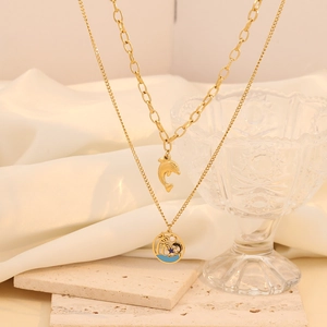Double-layered gold necklace with dolphin and coconut tree pendants on white fabric