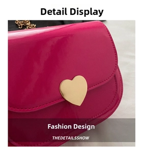 Close-up of fuchsia patent leather handbag with golden heart buckle and metal chain