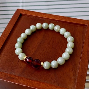 Detail of Nephrite jade bead bracelet with red garnets on a wooden display box