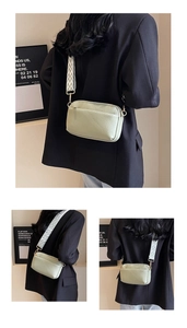 Detail of light green PU leather crossbody bag with wave patterned strap and gold hardware