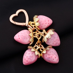 Detailed view of pink strawberry charms on a golden heart clasp over black leather