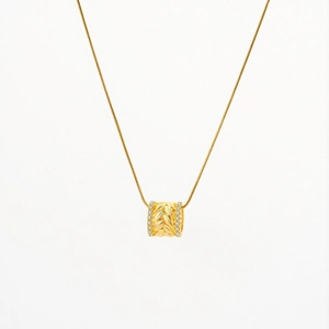 Macro view of a gold wheat ear barrel pendant necklace with sparkling stone accents