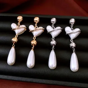 Vintage heart and pearl drop earrings in gold and silver finish displayed on leather box
