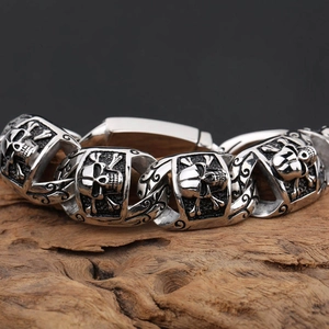 Men's retro punk skull bracelet in stainless steel displayed on a vintage wood block