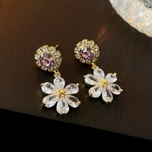 Macro detail of 18K gold plated flower earrings with purple and clear cubic zirconia