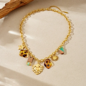 Bohemian gold plated necklace with amber resin and heart pendant on a sandy beach texture