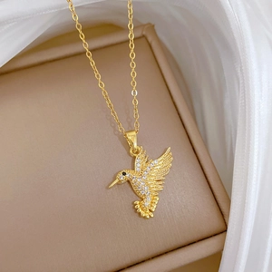 Macro view of gold hummingbird necklace with white zirconia pave and black gemstone eye detail