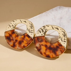 Detailed shot of round gold hammered metal earrings with amber tortoise shell finish