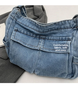 Detail of light blue denim shoulder bag with dual front pockets and contrast stitching