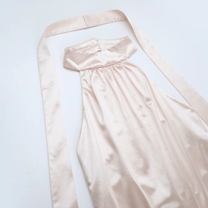 Détail d'une robe en satin champagne montrant l'encolure plissée et le lien à nouer