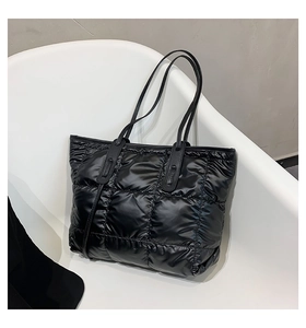 Detail of black quilted space cotton tote bag with puffy nylon texture on a chair