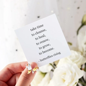 Detailed view of bicolor silver and gold butterfly ring held against white roses