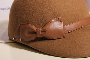 Detailed close-up of wool fedora featuring leather bow and sparkling rhinestone accents