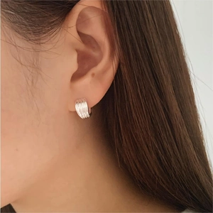 Close-up of minimalist sterling silver hoop earring with vertical stripe texture on ear