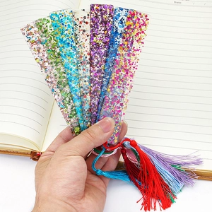 Handheld view of creative transparent acrylic bookmarks with colorful sequins and tassels
