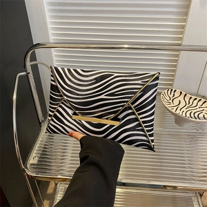 Macro detail of zebra print envelope clutch with luxury gold metal trim and snap closure