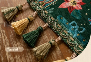 Detail of dark green Christmas table runner featuring poinsettia embroidery and colorful tassels
