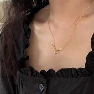 Close-up of minimalist gold double hook pendant necklace on black ruffle shirt