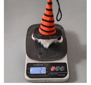 Weight display of Halloween gnome with orange striped hat and white beard on a digital scale