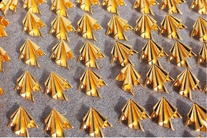 Macro shot of gold pleated fan-shaped metal earrings arranged on a textured grey background