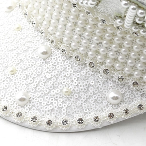 Macro detail of luxury wedding hat with white sequins, hand-sewn pearls and rhinestones