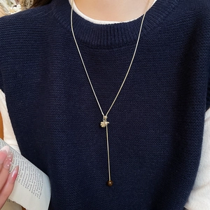 Detail shot of a long golden snake chain necklace with shell pendant and tiger eye bead