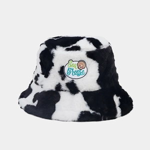 Detailed close-up of cow print plush bucket hat featuring a Sea Breeze embroidered patch