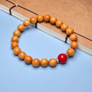 Close-up of sandalwood bead bracelet with red accent bead on vintage book background
