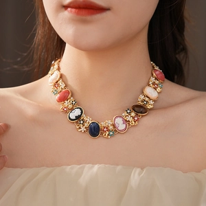 Detail of vintage gold necklace featuring colorful cameo portraits and sparkling crystals