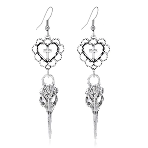 Vue macro de boucles d'oreilles gothiques argentées avec cœur, croix et crâne d'oiseau