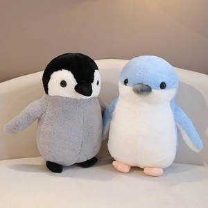 Cute plush penguin dolls in grey and blue colors on a soft sofa for children
